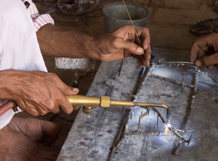 Two artisans crafting on a metal piece within an Archive.