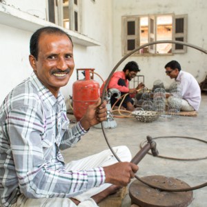 A man, Intizar Hussain, sitting in a workshop with a metal ring.