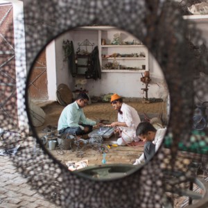 Khalil Ahmed and another man collaborate on a mirror in a workshop.