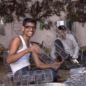 A man named Khalil Ahmed working in a workshop with a lot of metal pieces.