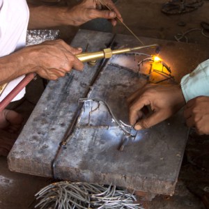 Khalil Ahmed and another man collaborating on a piece of metal.