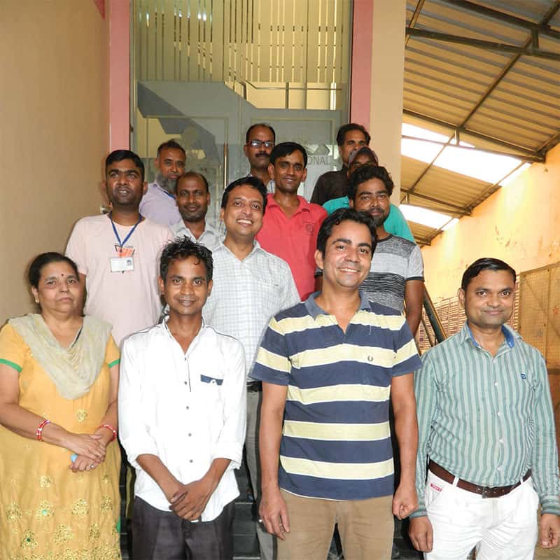 A team of people posing for a picture in a hallway.